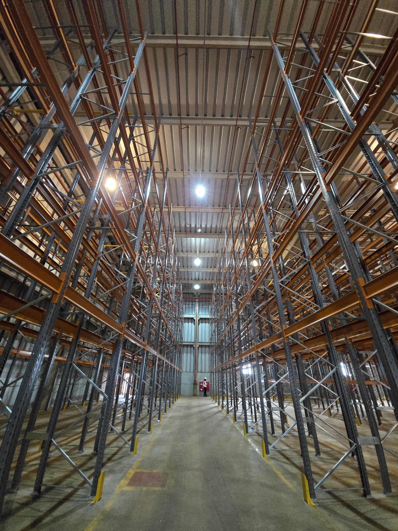 Corredor de porta-paletes em operação com empilhadeira e paletes organizados